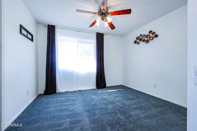 unfurnished room featuring dark colored carpet, ceiling fan, and a textured ceiling