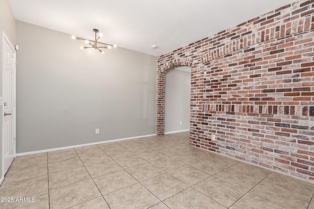 906 S 242nd Dr, Buckeye, AZ 85326 - spare room featuring brick wall, a chandelier, and light tile patterned flooring