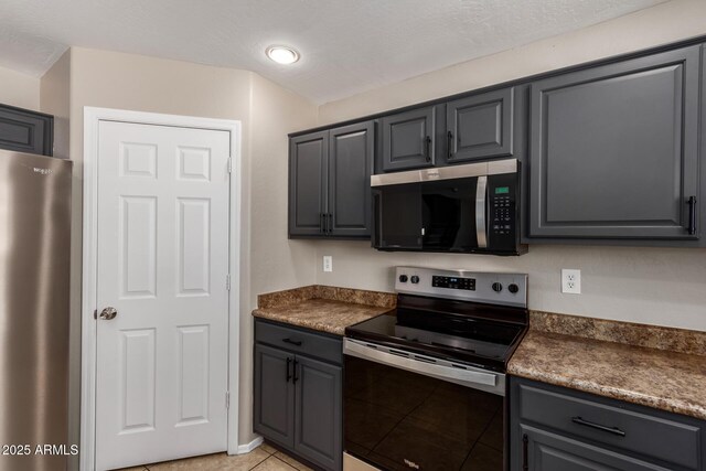 906 S 242nd Dr, Buckeye, AZ 85326 - kitchen with stainless steel appliances, dark countertops, light tile patterned floors, gray cabinetry, and recessed lighting