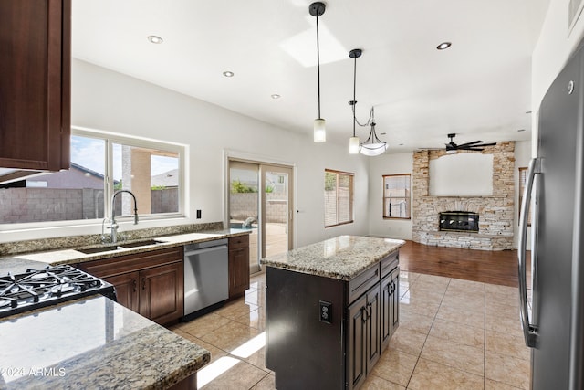 kitchen with ceiling fan, a center island, hanging light fixtures, stainless steel appliances, and light wood-type flooring