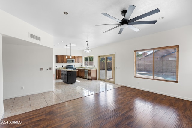 kitchen with a breakfast bar, ceiling fan, pendant lighting, light hardwood / wood-style flooring, and a kitchen island