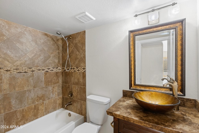 full bathroom featuring vanity, tiled shower / bath, a textured ceiling, and toilet