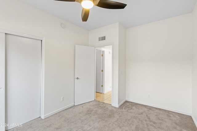 unfurnished bedroom with light carpet, a closet, and ceiling fan