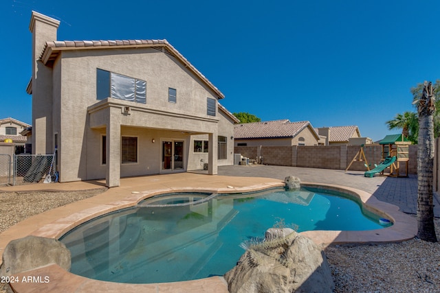 view of swimming pool with an in ground hot tub, a playground, and a patio area