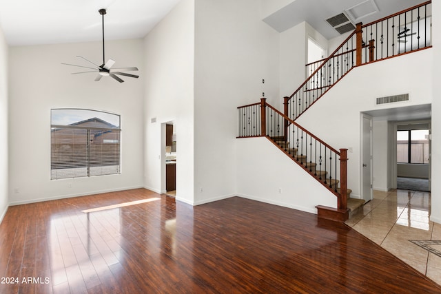 unfurnished living room with hardwood / wood-style flooring, ceiling fan, and high vaulted ceiling