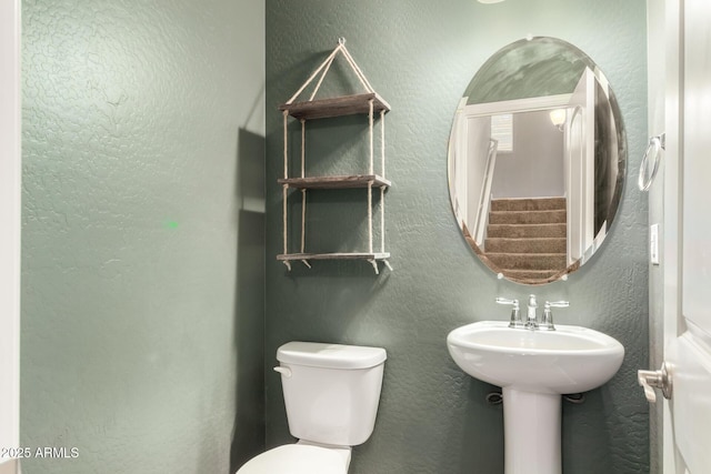 half bath with a textured wall and toilet