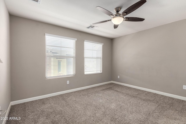 carpeted spare room with ceiling fan, visible vents, and baseboards