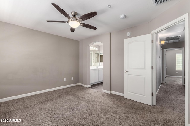 unfurnished bedroom featuring carpet floors, arched walkways, visible vents, and baseboards