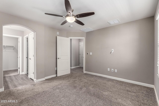 unfurnished bedroom featuring carpet floors, arched walkways, and baseboards