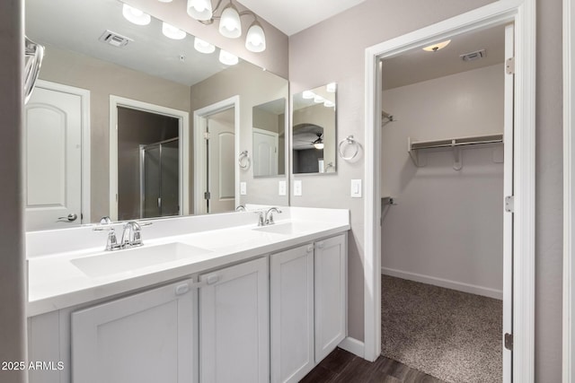 bathroom featuring visible vents, a sink, and a spacious closet