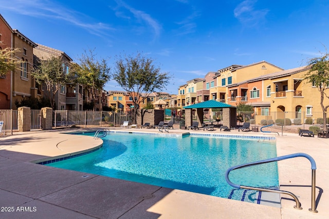 community pool featuring a residential view, fence, and a patio