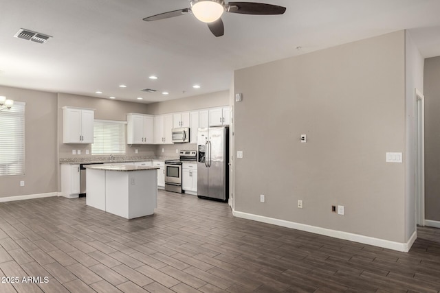 kitchen with stainless steel appliances, dark wood-style flooring, a kitchen island, visible vents, and white cabinetry