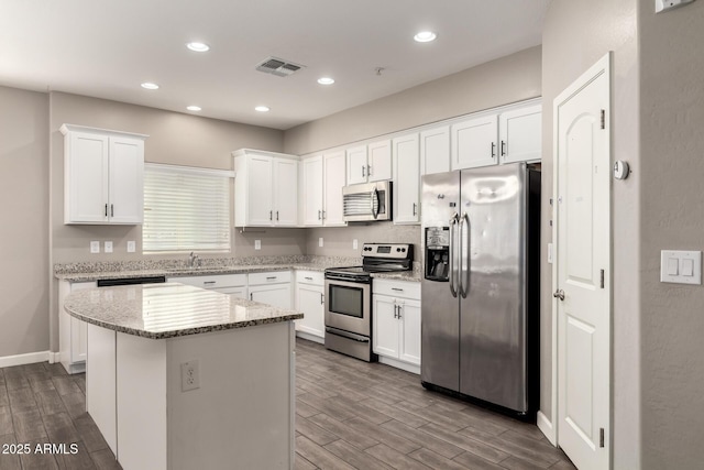 kitchen featuring visible vents, a kitchen island, appliances with stainless steel finishes, wood finish floors, and white cabinetry