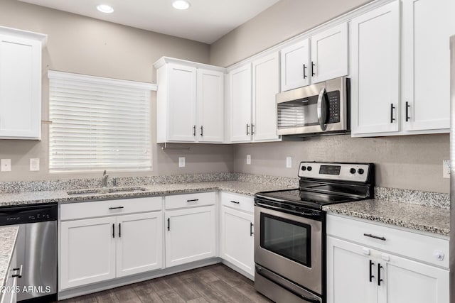 kitchen with wood finished floors, appliances with stainless steel finishes, a sink, and white cabinetry