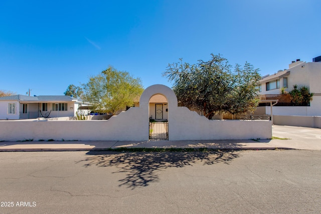 view of front facade with a fenced front yard, stucco siding, and a gate