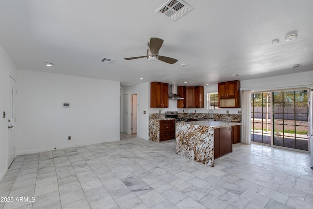 kitchen featuring visible vents, a sink, open floor plan, wall chimney exhaust hood, and stainless steel range with gas stovetop