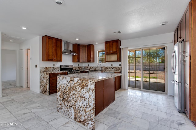 kitchen with visible vents, marble finish floor, a kitchen island, appliances with stainless steel finishes, and wall chimney range hood