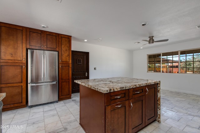 kitchen with visible vents, marble finish floor, a kitchen island, freestanding refrigerator, and ceiling fan