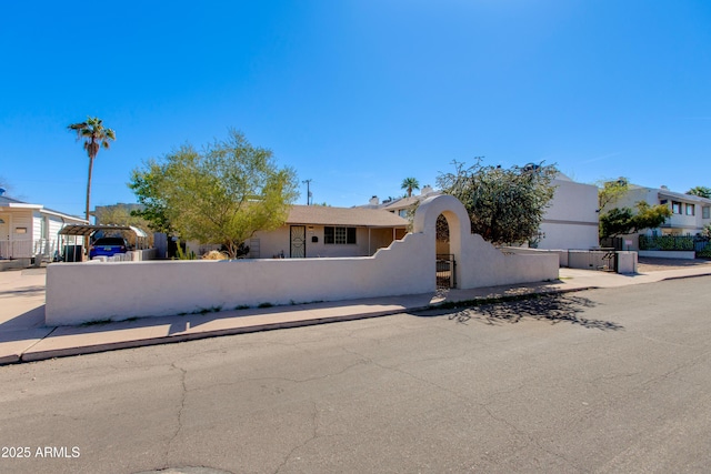 view of front of property with a carport, a fenced front yard, and stucco siding