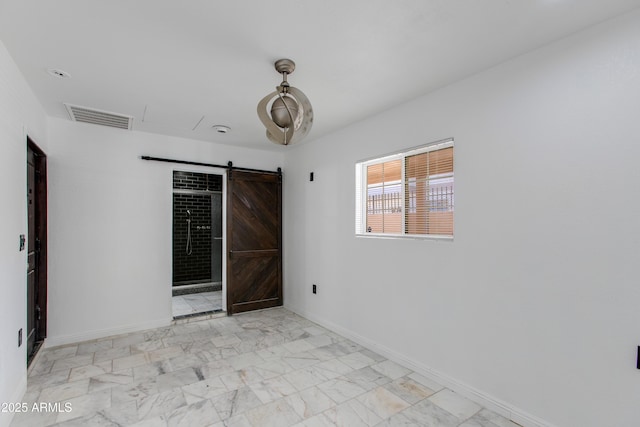 spare room with a barn door, baseboards, visible vents, and marble finish floor