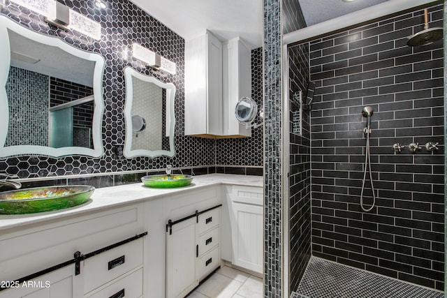 bathroom with tile patterned floors, a sink, tasteful backsplash, a tile shower, and double vanity