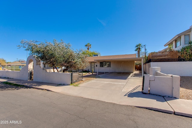 view of front of house with a gate, driveway, stucco siding, a carport, and a fenced front yard