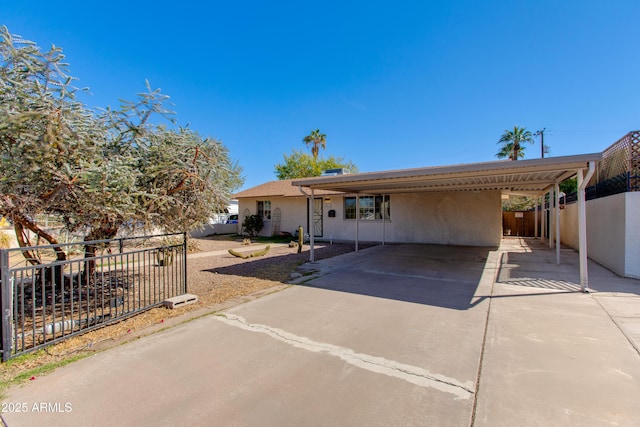 view of front of property with stucco siding, an attached carport, concrete driveway, and fence