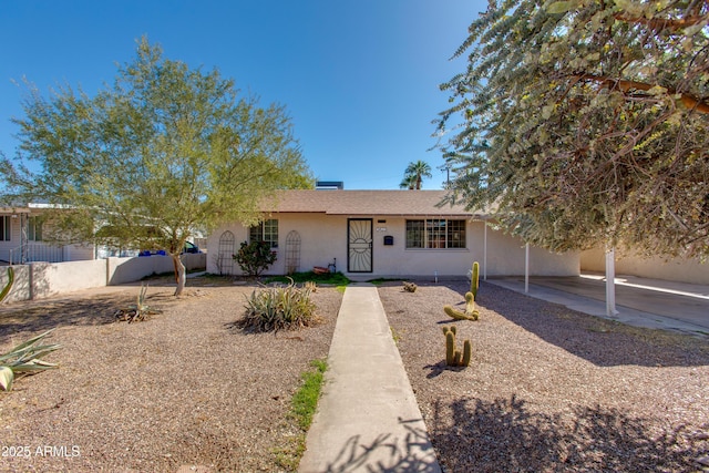 ranch-style house featuring a carport, stucco siding, and fence