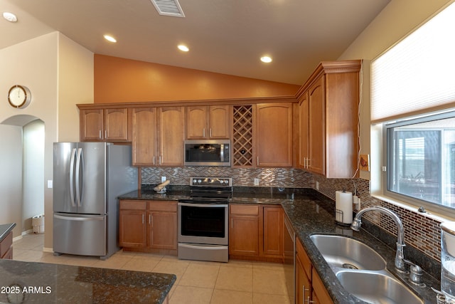 1398 W Sheep Wash Way, Benson, AZ 85602 - kitchen featuring stainless steel appliances, a sink, brown cabinets, tasteful backsplash, and vaulted ceiling