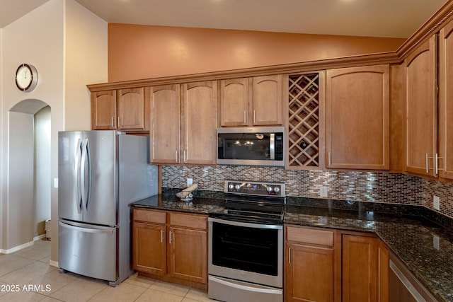 1398 W Sheep Wash Way, Benson, AZ 85602 - kitchen featuring appliances with stainless steel finishes, lofted ceiling, backsplash, arched walkways, and dark stone countertops