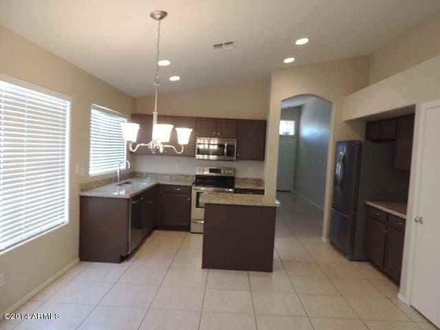 kitchen featuring visible vents, arched walkways, a kitchen island, appliances with stainless steel finishes, and hanging light fixtures