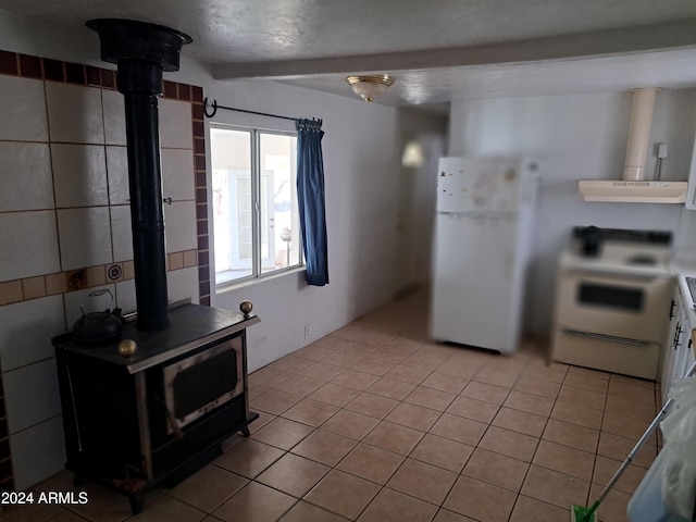 kitchen featuring beam ceiling, range hood, light tile patterned floors, and white appliances