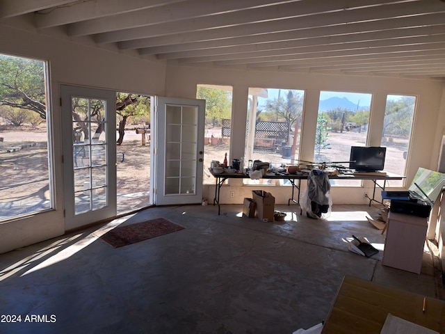 unfurnished sunroom with beam ceiling, french doors, and a healthy amount of sunlight