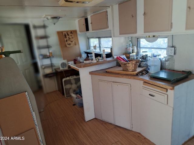 kitchen with white cabinets, kitchen peninsula, and light hardwood / wood-style flooring