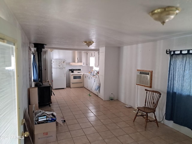 kitchen with a wall mounted air conditioner, white appliances, sink, light tile patterned floors, and white cabinets