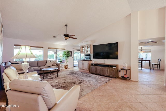 living room with a textured ceiling, ceiling fan, light tile patterned flooring, and high vaulted ceiling