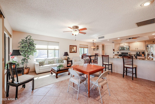 dining area featuring a textured ceiling, ceiling fan, and light tile patterned flooring