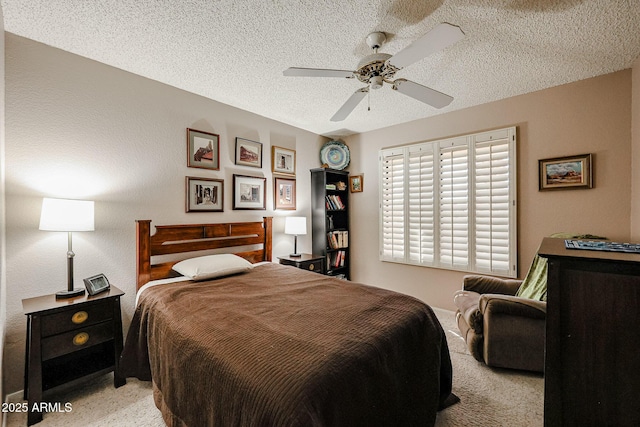 bedroom with a textured ceiling, ceiling fan, and light carpet