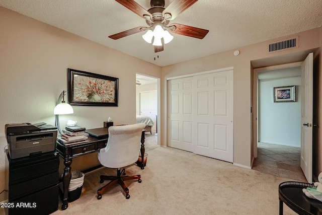 carpeted office featuring ceiling fan and a textured ceiling