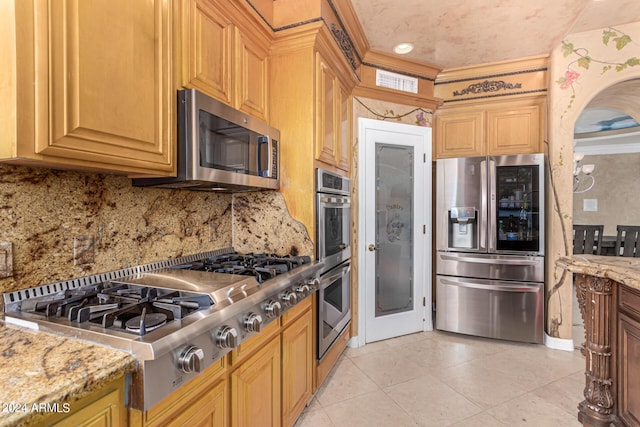 kitchen featuring stainless steel appliances, light tile patterned flooring, light stone countertops, and decorative backsplash