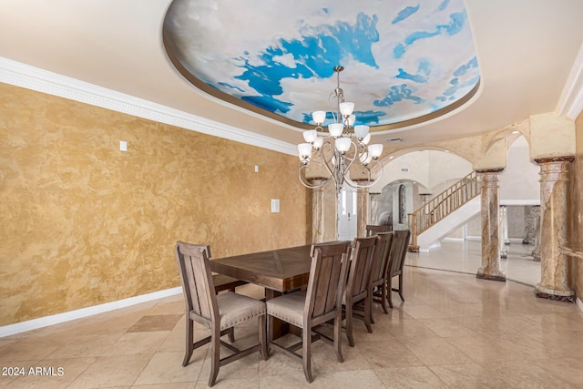 dining space featuring an inviting chandelier, ornamental molding, a tray ceiling, and decorative columns