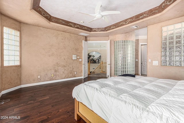 bedroom featuring crown molding, dark hardwood / wood-style floors, a raised ceiling, and ceiling fan