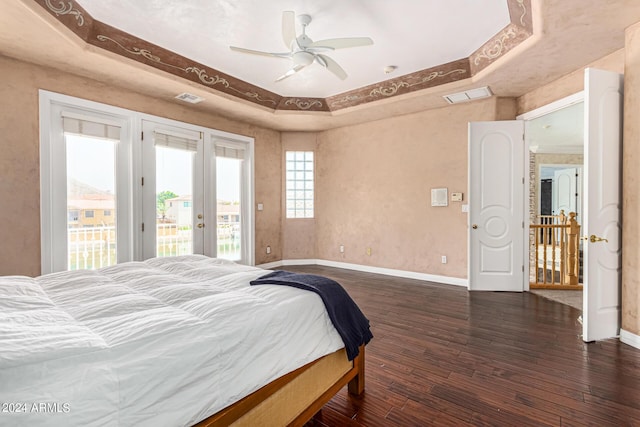 bedroom with french doors, access to outside, a tray ceiling, dark hardwood / wood-style flooring, and ceiling fan