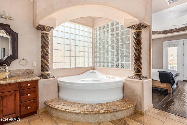 bathroom featuring decorative columns, vanity, and a tub