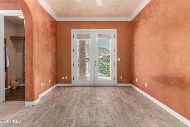 empty room with ornamental molding, light wood-type flooring, and french doors