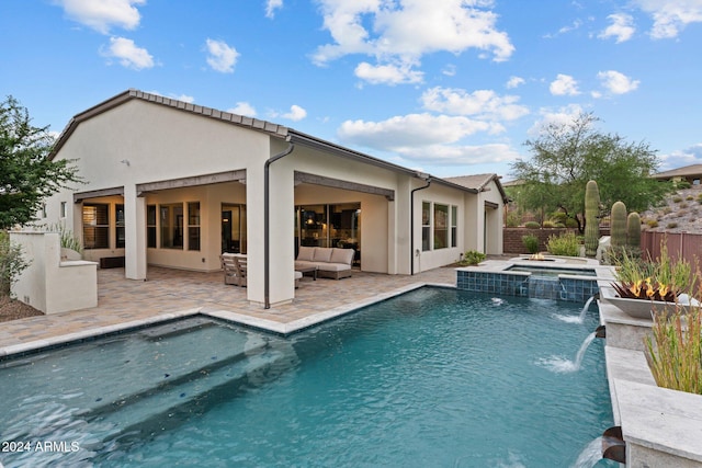 back of property with a swimming pool with hot tub, pool water feature, and a patio area