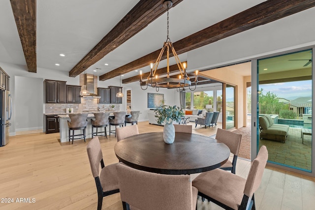 dining room with beam ceiling, a chandelier, and light wood-type flooring