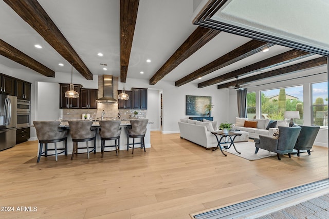 living room featuring beamed ceiling, light hardwood / wood-style flooring, and ceiling fan