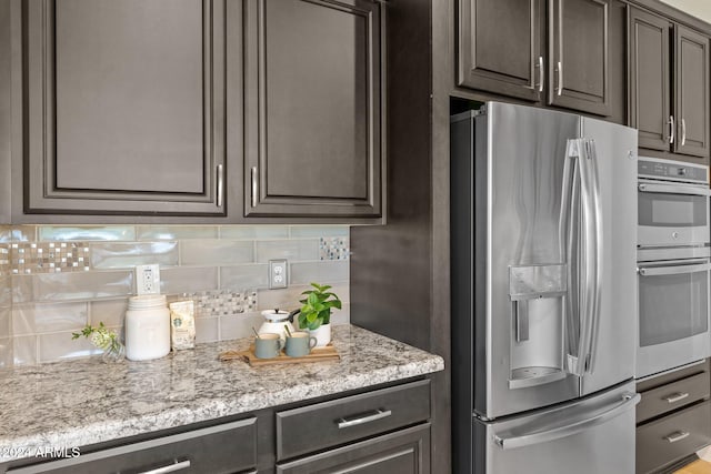 kitchen featuring light stone countertops, appliances with stainless steel finishes, dark brown cabinetry, and backsplash