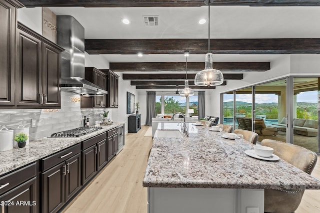 kitchen featuring a large island with sink, tasteful backsplash, a kitchen bar, and stainless steel gas stovetop